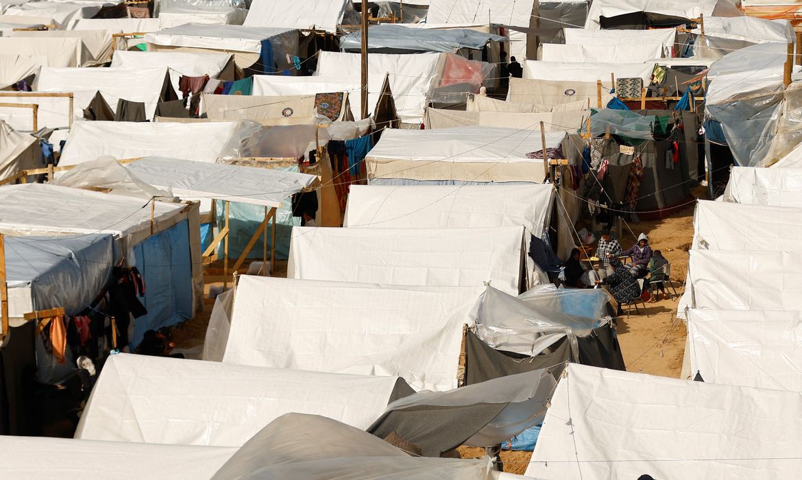 Displaced Palestinians sit by tents, amid the ongoing conflict between Israel and Palestinian Islamist group Hamas, in a tent camp in Khan Younis in the southern Gaza Strip, November 20, 2023. REUTERS/Ibraheem Abu Mustafa